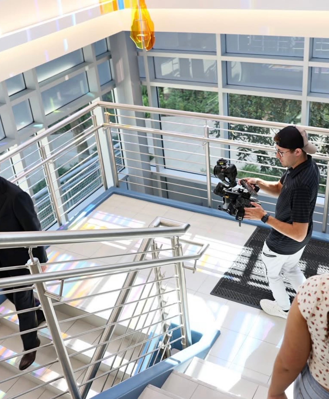 Aidan filming inside a modern atrium stairwell